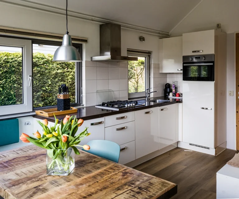 eethoek Zeebungalows Moderne keuken met houten tafel, tulpenboeket en elektrische apparatuur.