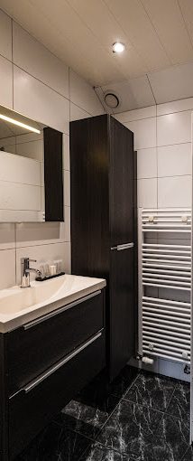 Moderne badkamer met een wastafel, spiegel, kast en handdoekenradiator.