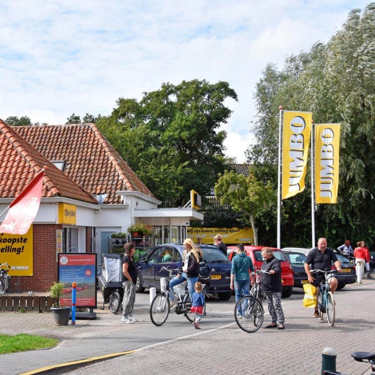 supermarkt Formerum Drukke straat met winkel, mensen te voet en op fietsen, herkenbare Jumbo-vlaggen.