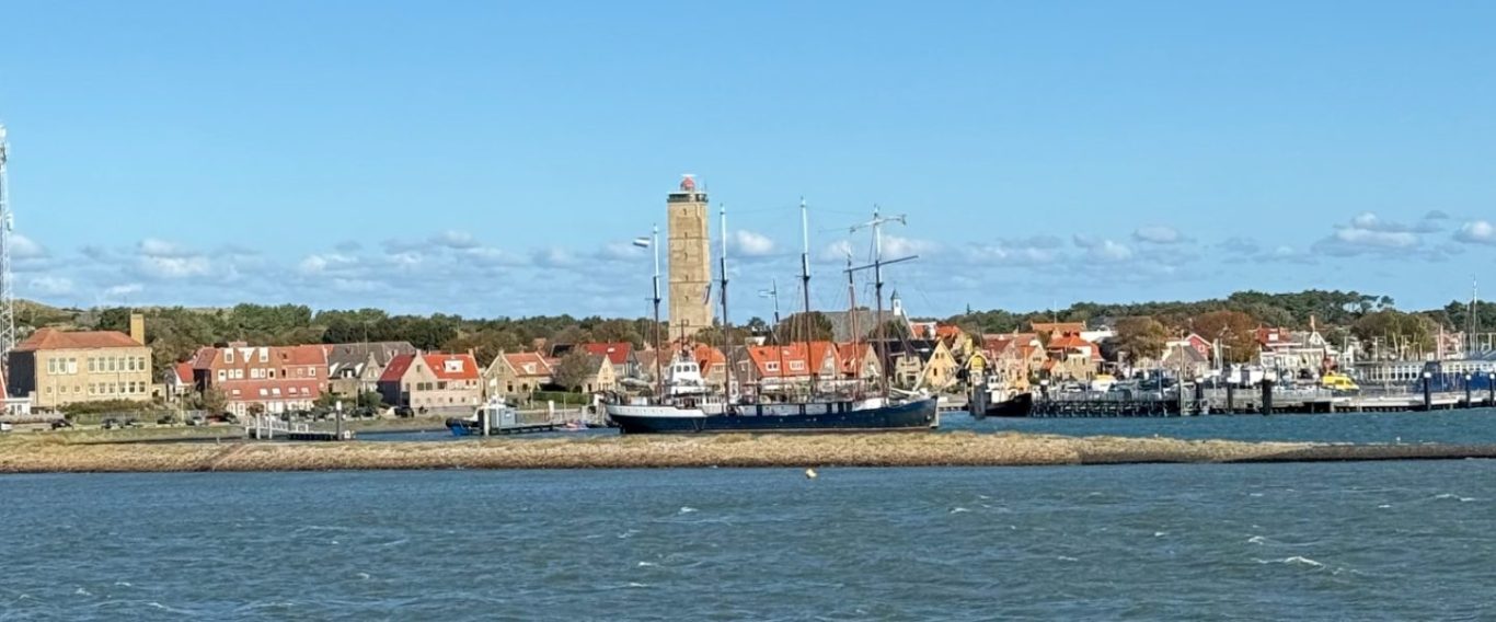 Haven van Terschelling met schepen en een Brandaris; schilderachtig uitzicht op een stad aan het water.