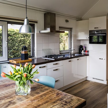Moderne keuken met houten tafel, bloemenvaas en inbouwapparatuur.